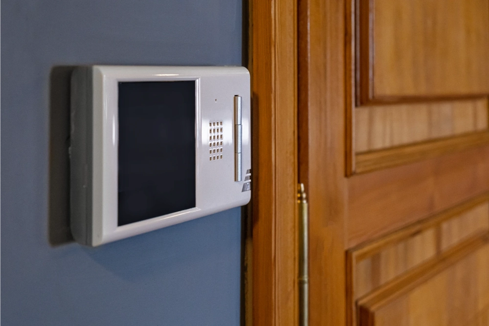 Panel domofonowy z kolorowym wyświetlaczem zamontowany przy drewnianych drzwiach Domofony